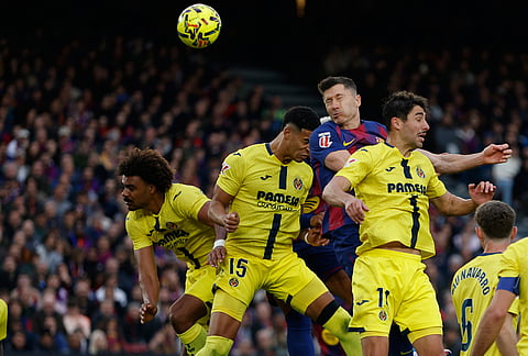 Barcelona's Robert Lewandowski, top, heads the ball during the Spanish La Liga soccer match between Barcelona and Villareal in Barcelona, Spain.