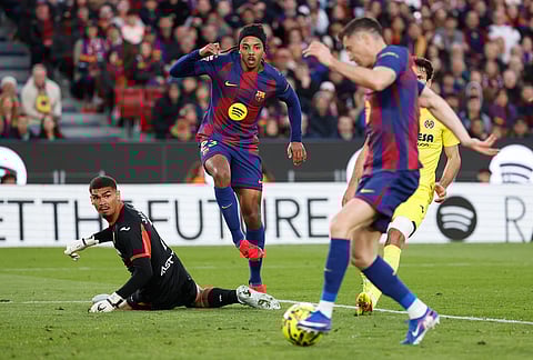 Barcelona's Jules Kounde, center, looks as teammate Robert Lewandowski scores his side's 4th goal during the Spanish La Liga soccer match between Barcelona and Villareal in Barcelona, Spain.