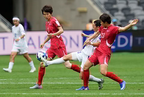 Uzbekistan's Diyorakhon Khabibullaeva, centre, battles for the ball with North Korea's Ri Hye Gyong, right, and Myong Yu Jong during the Women's Asia Cup soccer match between North Korea and Uzbekistan in Sydney.