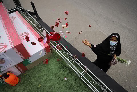A woman throws rose petals on the coffins during funeral of mostly children killed in what Iranian officials said was an Israeli-U.S. strike Feb. 28 on a girls' elementary school in Minab, Iran.