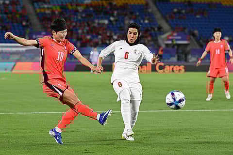South Korea's Ji So-yun takes a shot at goal past Zahra Sarbali, right, of Iran during the Women's Asia Cup soccer match between Iran and South Korea on the Gold Coast, Australia.