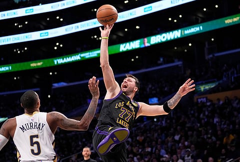 Los Angeles Lakers guard Luka Doncic, right, shoots as New Orleans Pelicans guard Dejounte Murray defends during the second half of an NBA basketball game in Los Angeles. 