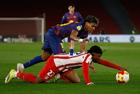 Atletico Madrid's Giacomo Raspadori, bottom, and Barcelona's Lamine Yamal challenge for the ball during the Copa del Rey semifinal second leg soccer match between Barcelona and Atletico Madrid in Barcelona, Spain.