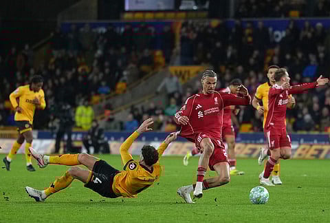 Liverpool's Hugo Ekitike, right, is pulled back by Wolverhampton Wanderers' Santiago Bueno during the English Premier League soccer match between Wolverhampton Wanderers and Liverpool in Wolverhampton, England.