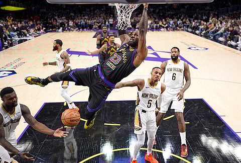 Los Angeles Lakers forward LeBron James, center, finishes his dunks as New Orleans Pelicans forward Zion Williamson, left, guard Dejounte Murray, second from right, and center DeAndre Jordan, right, defend during the first half of an NBA basketball game in Los Angeles.
