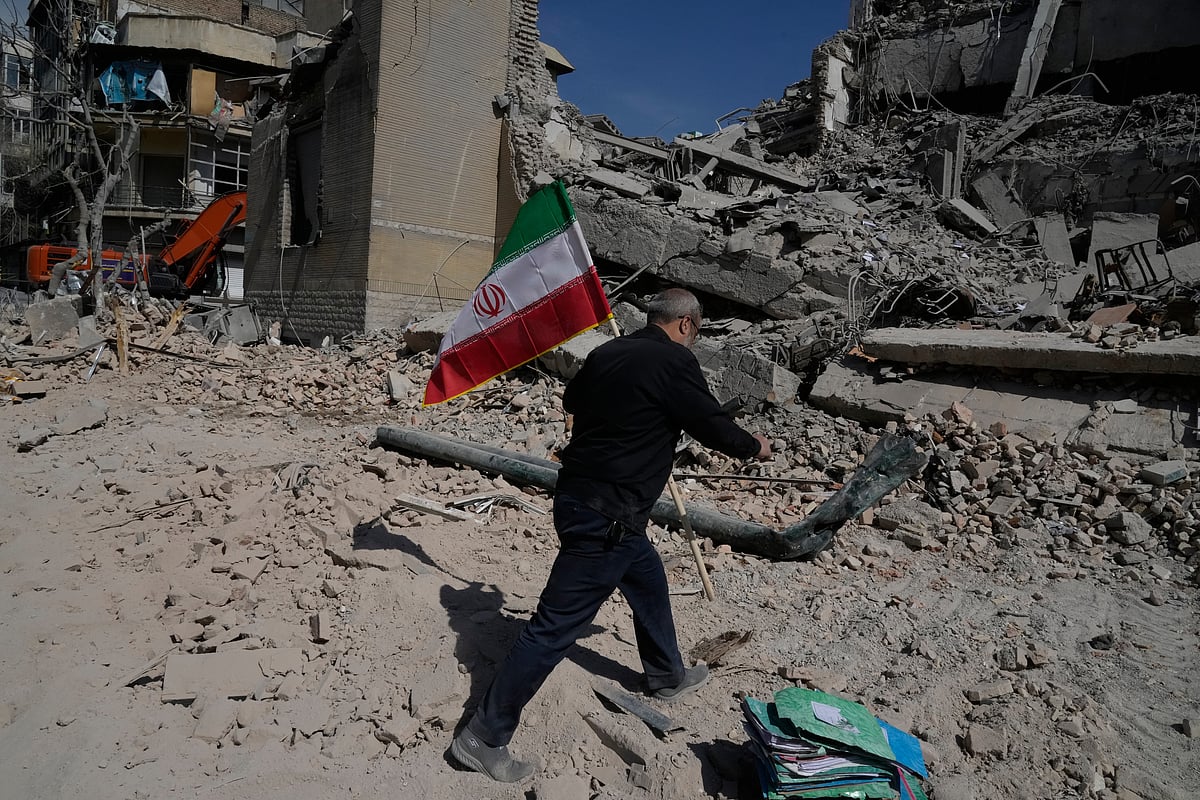 A man carries an Iranian flag to place on the rubble of a police facility struck during the U.S.–Israeli military campaign in Tehran, Iran, Wednesday, March 4, 2026.  - AP