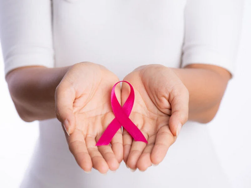 Person holding pink ribbon for breast cancer awareness in open hands