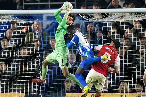 Arsenal's goalkeeper David Raya saves in front pf Brighton's Yankuba Minteh during the Premier League soccer match between Brighton and Arsenal in Brighton, England.