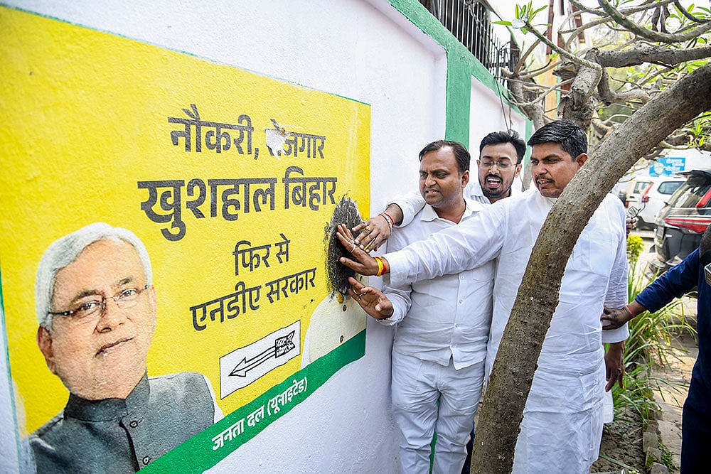 JD(U) workers smear black ink on a wall during a protest against the decision of Bihar Chief Minister Nitish Kumar to enter the Rajya Sabha, a move seen as signalling the end of his more than two-and-a-half-decade-long stint in state politics, in Patna. - | Photo: PTI 