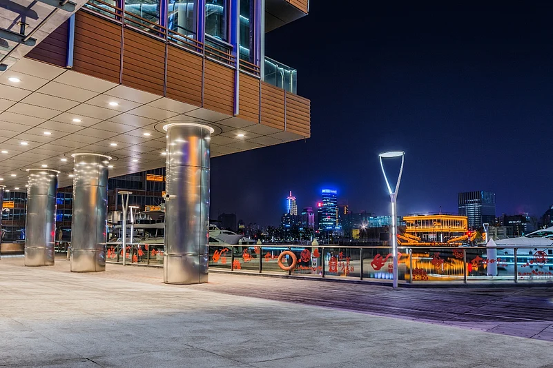 Modern waterfront walkway at night with city lights