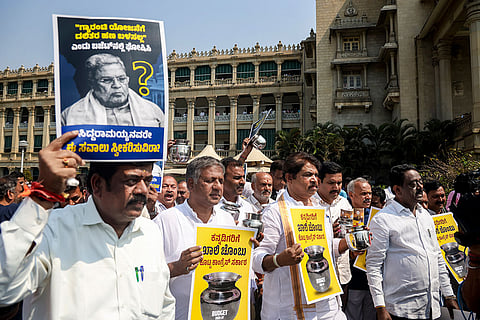 Leader of Opposition in the Karnataka Assembly R Ashoka, BJP state president B Y Vijayendra and others hold empty vessels and placards during 'Khaali Chambu' protest amid the state Budget session, at the Vidhana Soudha premises, in Bengaluru. The opposition BJP in Karnataka on Friday staged a protest saying that the budget presented by Chief Minister Siddaramaiah is an empty vessel, which has nothing to offer to people. 