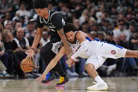 San Antonio Spurs guard Dylan Harper, left, and Detroit Pistons guard Cade Cunningham, right, scramble for a loose ball during the second half of an NBA basketball game in San Antonio.