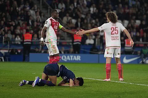 PSG's Pedro Fernandez, bottom, reacts on the pitch as Monaco's Denis Zakaria, left, and Wout Faes shake hands during the French League One soccer match between Paris Saint-Germain and Monaco in Paris.