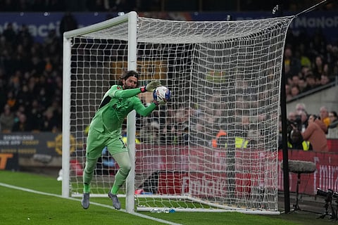 Liverpool's goalkeeper Alisson saves the ball during the English FA Cup soccer match between Wolves and Liverpool in Wolverhampton, England.