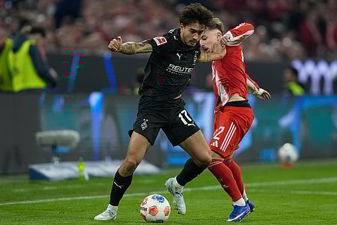 Moenchengladbach's Jens Castrop, left, and Bayern's Lennart Karl challenge for the ball during the Bundesliga soccer match between FC Bayern Munich and Borussia Moenchengladbach in Munich, Germany.