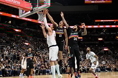 Los Angeles Clippers center Brook Lopez, left, goes to the basket against San Antonio Spurs' Carter Bryant, center, and Julian Champagnie during the second half of an NBA basketball game in San Antonio.