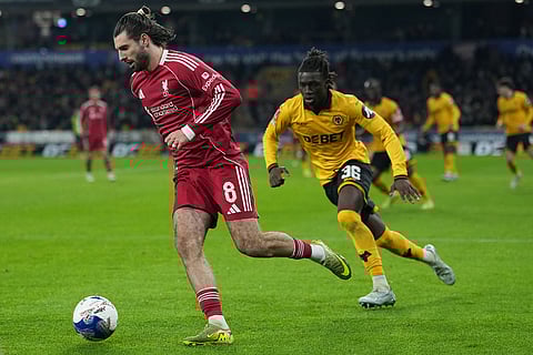 Liverpool's Dominik Szoboszlai, left, and Wolverhampton Wanderers' Mateus Mane challenge for the ball during the English FA Cup soccer match between Wolves and Liverpool in Wolverhampton, England.