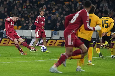Liverpool's Andrew Robertson, left scores during the English FA Cup soccer match between Wolves and Liverpool in Wolverhampton, England.