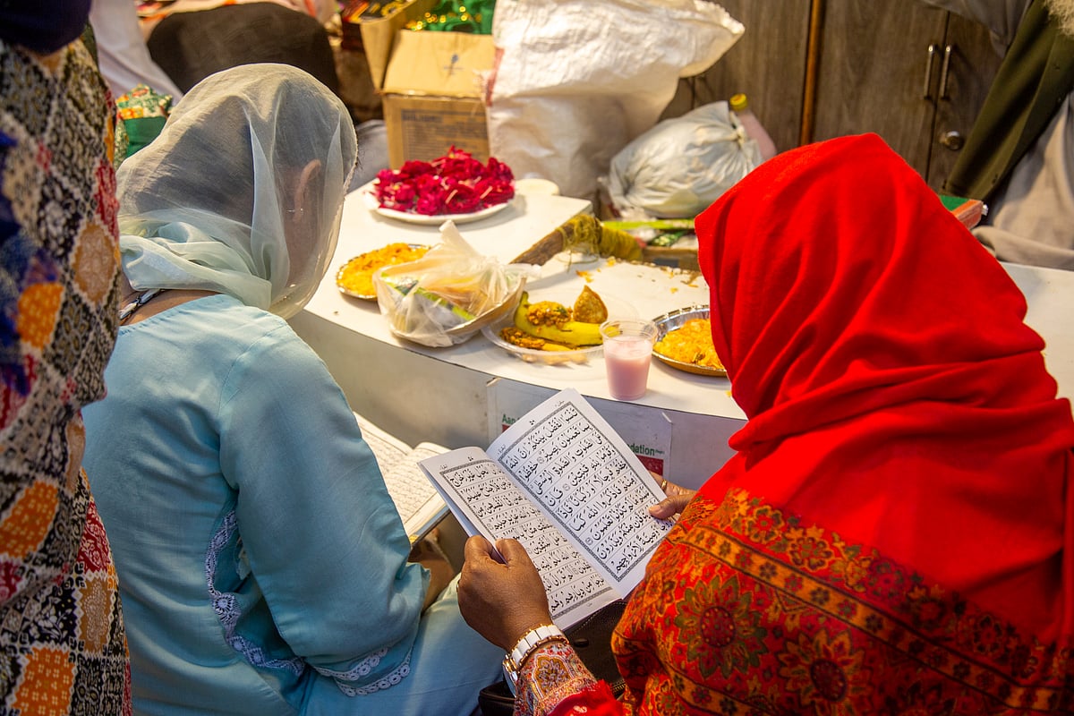 Two women read while waiting to break their fast at Nizamuddin Dargah during Ramadan. - PALANIKUMAR