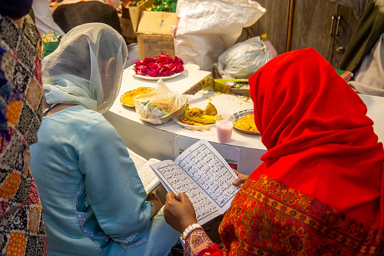 Two women read while waiting to break their fast at Nizamuddin Dargah during Ramadan. - PALANIKUMAR