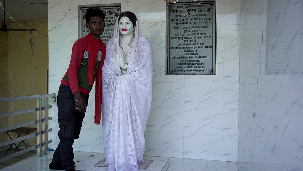 Anmol, a local villager takes us to the house of Phoolan Devi in Shekhpur Guda. As he unveils the Statue from its “ghoongat”, he stops to pose with it for the camera - | Photo:  Animikh Chakrabarty/Outlook