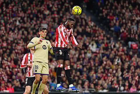 Athletic Bilbao's Inaki Williams, top, heads the ball past Barcelona's Gerard Martin during the Spanish La Liga soccer match between Athletic Bilbao and Barcelona in Bilbao, Spain.
