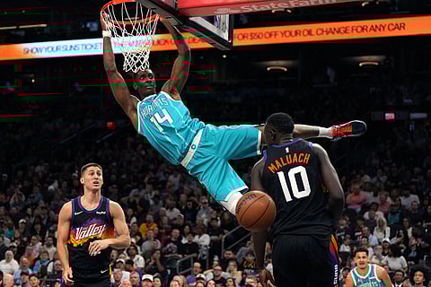 Charlotte Hornets forward Moussa Diabate (14) dunks over Phoenix Suns guard Collin Gillespie and center Khaman Maluach (10) during the second half of an NBA basketball game in Phoenix.