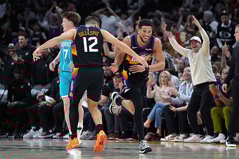 Phoenix Suns guard Devin Booker, center right, celebrates with guard Collin Gillespie (12) after scoring against the Charlotte Hornets during the second half of an NBA basketball game in Phoenix.
