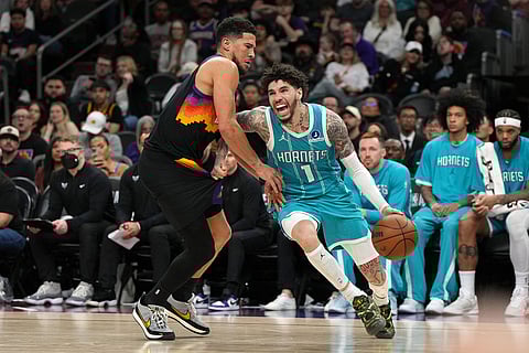 Charlotte Hornets guard LaMelo Ball (1) drives on Phoenix Suns guard Devin Booker during the second half of an NBA basketball game in Phoenix.