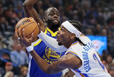 Oklahoma City Thunder guard Shai Gilgeous-Alexander, front, goes to the basket against Golden State Warriors forward Draymond Green, back, during the first half of an NBA basketball game in Oklahoma City. 