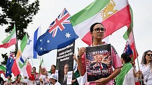 | Photo: AP/DAVE HUNT : Iranians in Australia react with flags and political signs outside the stadium ahead of the Women's Asia Cup soccer match between Australia and Iran in Robina, Australia, Thursday, March 5, 2026.
