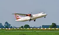 Alliance Air regional aircraft departs the airport, climbing above a grassy runway in Uttar Pradesh