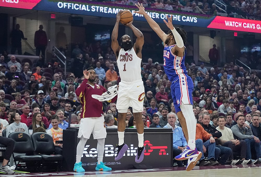 Cleveland Cavaliers guard James Harden (1) shoots as Philadelphia 76ers forward Trendon Watford (12) defends and teammate Donovan Mitchell, left, looks on in the first half of an NBA basketball game in Cleveland. - | Photo: AP/Sue Ogrocki