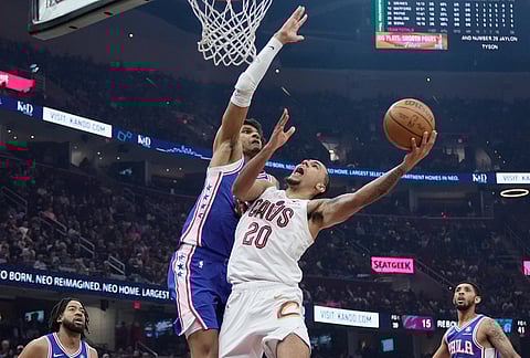 Cleveland Cavaliers guard Jaylon Tyson (20) shoots as Philadelphia 76ers forward Dominick Barlow, left, defends in the first half of an NBA basketball game in Cleveland.