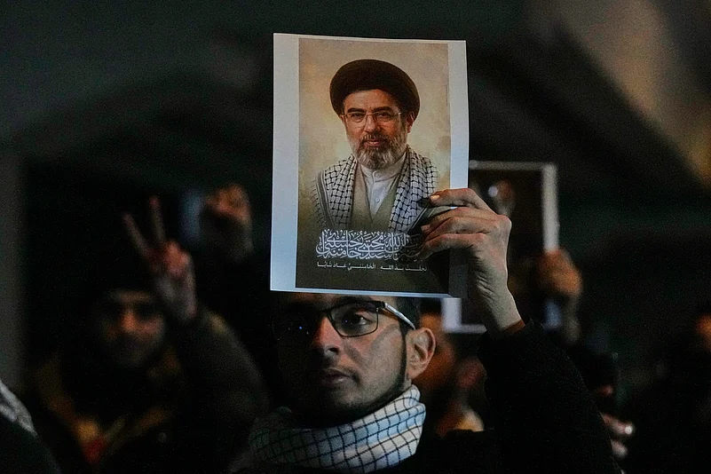 Iraqis hold a portrait of the new successor to Supreme Leader, Ayatollah Mojtaba Khamenei