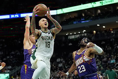 Milwaukee Bucks' Kyle Kuzma (18) drives to the basket between Phoenix Suns' Jordan Goodwin (23) and Grayson Allen during the first half of an NBA basketball game in Milwaukee.