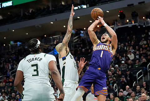Phoenix Suns' Devin Booker (1) shoots against Milwaukee Bucks' Kyle Kuzma during the second half of an NBA basketball game, in Milwaukee.
