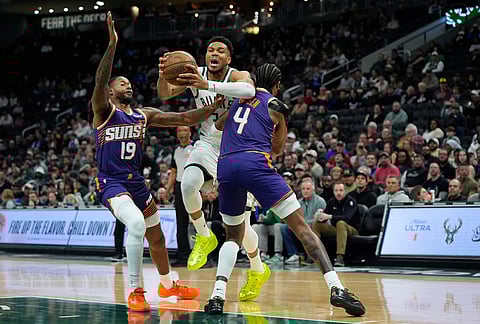 Milwaukee Bucks' Giannis Antetokounmpo (34) drives to the basket between Phoenix Suns' Jalen Green (4) and Haywood Highsmith (19) during the first half of an NBA basketball game in Milwaukee.