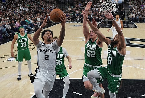 San Antonio Spurs guard Dylan Harper (2) drives to the basket against Boston Celtics guard Derrick White (9) and center Luka Garza (52) during the second half of an NBA basketball game in San Antonio.