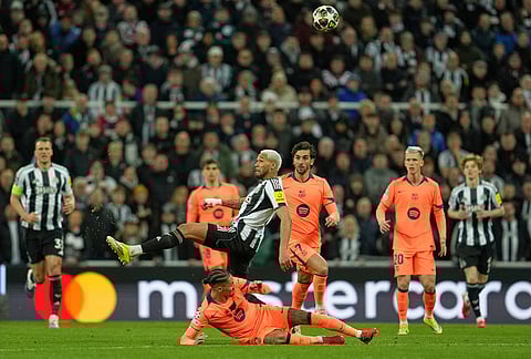 Newcastle's Joelinton, top, and Barcelona's Raphinha battle for the ball during the Champions League round of 16 first leg soccer match between Newcastle United and Barcelona in Newcastle, England.