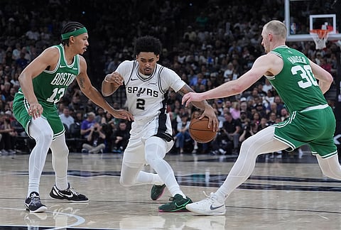 San Antonio Spurs guard Dylan Harper (2) drives between Boston Celtics guard Ron Harper Jr. (13) and forward Sam Hauser (30) during the second half of an NBA basketball game in San Antonio.