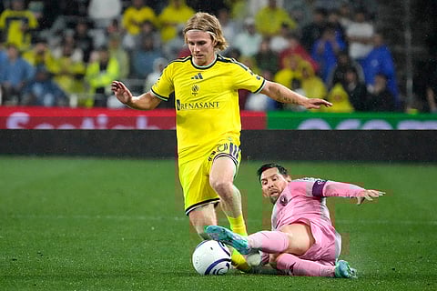 Inter Miami forward Lionel Messi falls as he tries to stop the charge of Nashville SC midfielder Edvard Tagseth, left, in the second half of a CONCACAF Champions Cup Round of 16 soccer match in Nashville, Tenn.