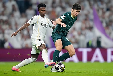 Real Madrid's Vinicius Junior, left, and Manchester City's Abdukodir Khusanov fight for the ball during a first leg round of 16 Champions League soccer match between Real Madrid and Manchester City in Madrid, Spain.