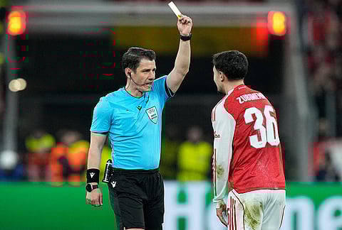 Turkish referee Umut Meler, left, shows the yellow card to Arsenal's Martin Zubimendi during the Champions League round of 16 first leg soccer match between Bayer Leverkusen and Arsenal FC in Leverkusen, Germany.