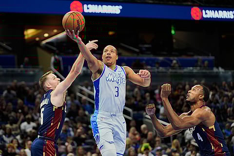 Orlando Magic guard Desmond Bane (3) makes a shot as he gets between Cleveland Cavaliers guard Sam Merrill, left, and center Evan Mobley during the first half of an NBA basketball game in Orlando, Fla.