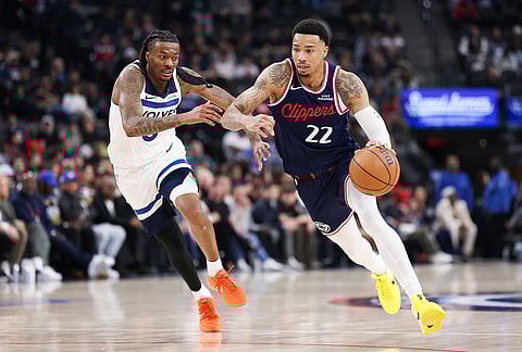 Los Angeles Clippers guard Jordan Miller (22) dribbles against Minnesota Timberwolves guard Bones Hyland, left, during the first half of an NBA basketball game, in Inglewood, California.