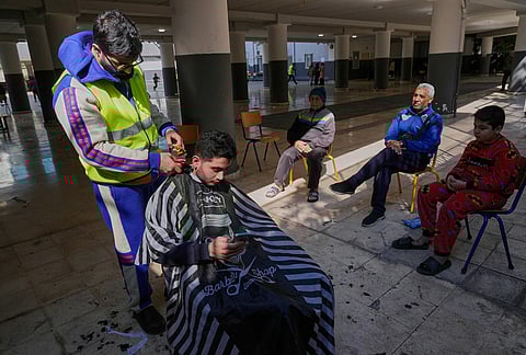 A displaced man who fled Israeli strikes in southern Lebanon receives a haircut in the playground of a school turned into a shelter in Beirut, Lebanon, Tuesday, March 10, 2026. 