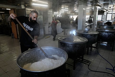 Volunteers cook meals for displaced people who fled Israeli airstrikes in southern Lebanon and Dahiyeh, Beirut's southern suburbs, at the Bir Hassan Technical Institute, which has been turned into a shelter, in Beirut, Lebanon, Wednesday, March 11, 2026. 