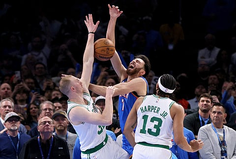 Boston Celtics forward Sam Hauser, left, fouls Oklahoma City Thunder center Chet Holmgren as Celtics guard Ron Harper Jr. (13) looks on in the second half of an NBA basketball game in Oklahoma City. 