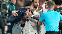 | Photo: AP/Michel Euler : Chelsea's Pedro Neto, center, embraces a ballboy who he pushed in a rush to get the ball back in play, during the first leg of the Champions League round of 16 soccer match between Paris Saint-Germain and Chelsea, in Paris, Wednesday, March 11, 2026. 